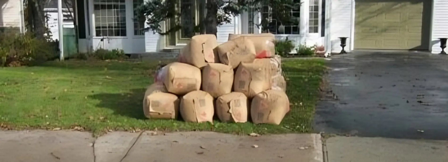 filled paper yard waste bags piled together on a lawn