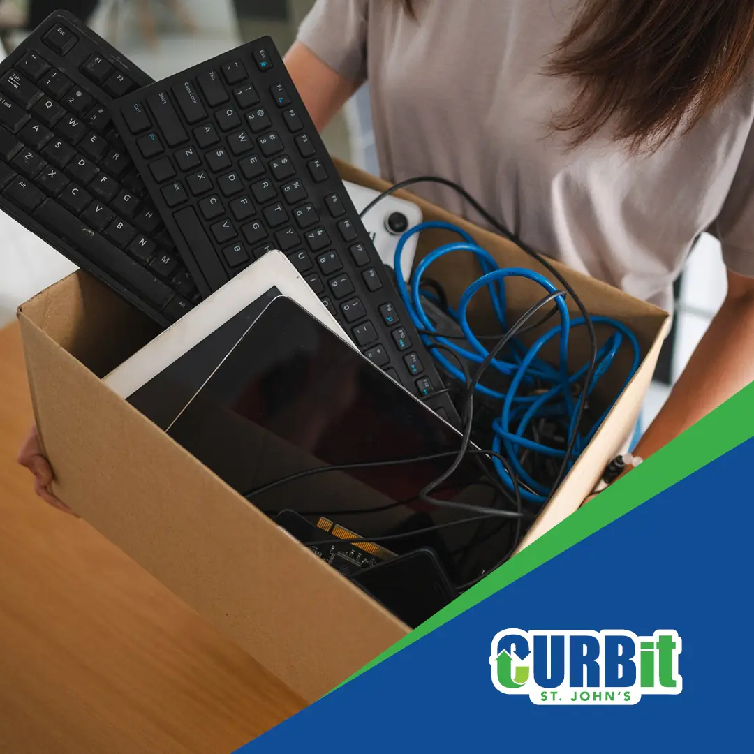 electronic devices including keyboard, cords and mobile devices in a cardboard box ready to drop off for electronic waste recycling